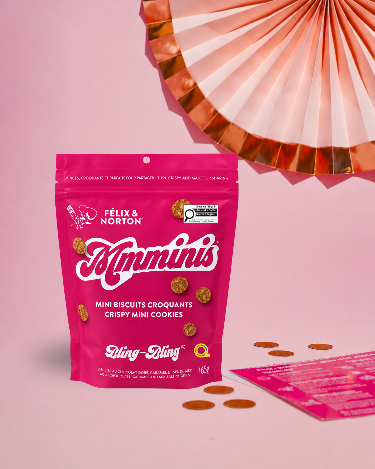 A pink stand-up pouch of Félix & Norton Mimminis mini biscuits croquants, displayed on a pink background with a folded paper fan and scattered mini cookies.